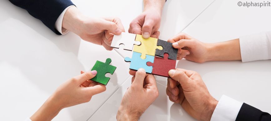 Hände mit Puzzle-Teilen über Tisch 